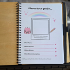 Aufgeschlagenes Erinnerungsbuch zur Einschulung mit farbig gestalteter Ausfüllseite, Platz für ein Erinnerungsfoto und Zeilen für eigene Notizen.