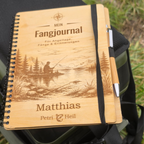 Personalisiertes Fangjournal aus Holz auf einer Angeltasche am See